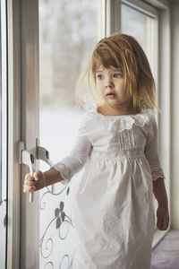 Side view of young woman looking through window