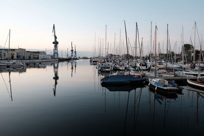 Boats moored in harbor at sunset