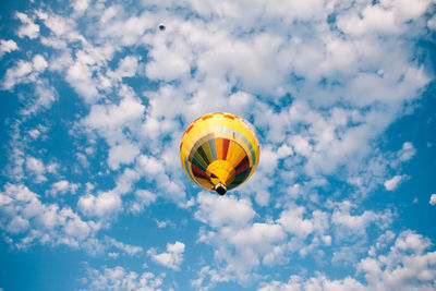 Low angle view of hot air balloons flying against cloudy sky