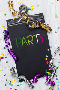 High angle view of colorful confetti with party text on clipboard over table