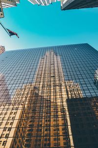 Low angle view of skyscrapers against blue sky