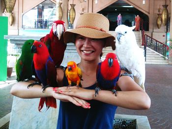 Happy woman in hat holding parrots