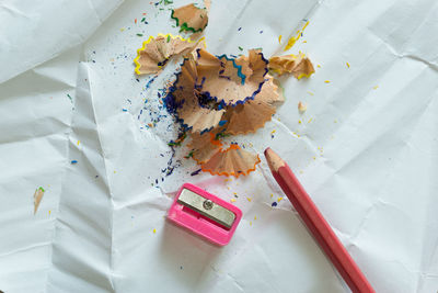 High angle view of pencils and shavings by sharpener on paper