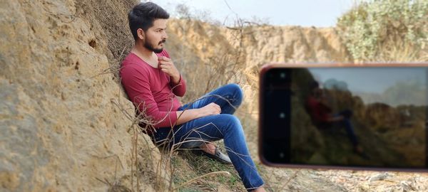 Side view of young man using mobile phone outdoors