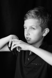 Portrait of boy standing against black background