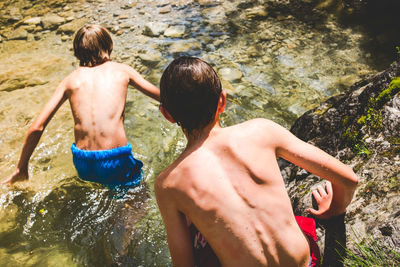 Rear view of shirtless boys in water