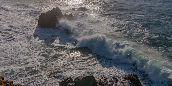 Panoramic high angle view of large wave breaking onto rocky coastline