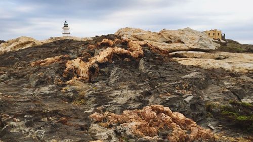 Low angle view of cliff against cloudy sky