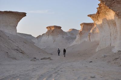 Rear view of tourist walking amidst sandstones
