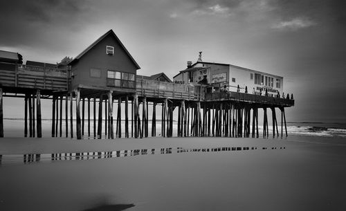 Pier on beach against cloudy sky