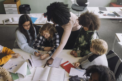 Teacher pointing at book while teaching in classroom