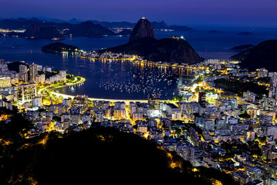 High angle view of illuminated city by sea