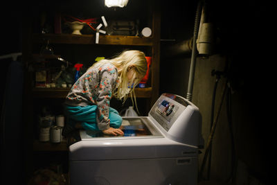 Little girl sitting on washing machine