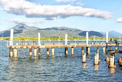 Wooden posts in lake against sky