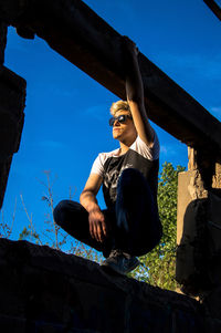 Low angle view of woman sitting against sky