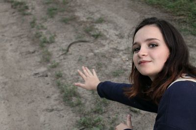 Portrait of smiling young woman showing thumbs up on road