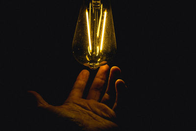 Close-up of illuminated light bulb over black background