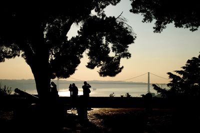 Silhouette people on beach against sky during sunset