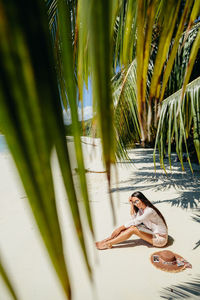 Side view of woman sitting at beach during summer