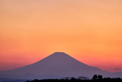 Scenic view of silhouette mountains against orange sky