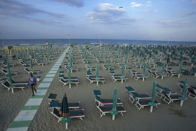 Deck chairs on beach against sky