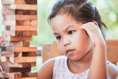 Girl playing with wooden toy blocks while sitting in porch