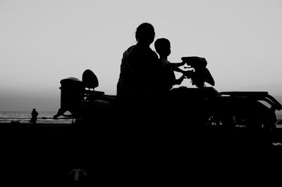 Silhouette people sitting against clear sky