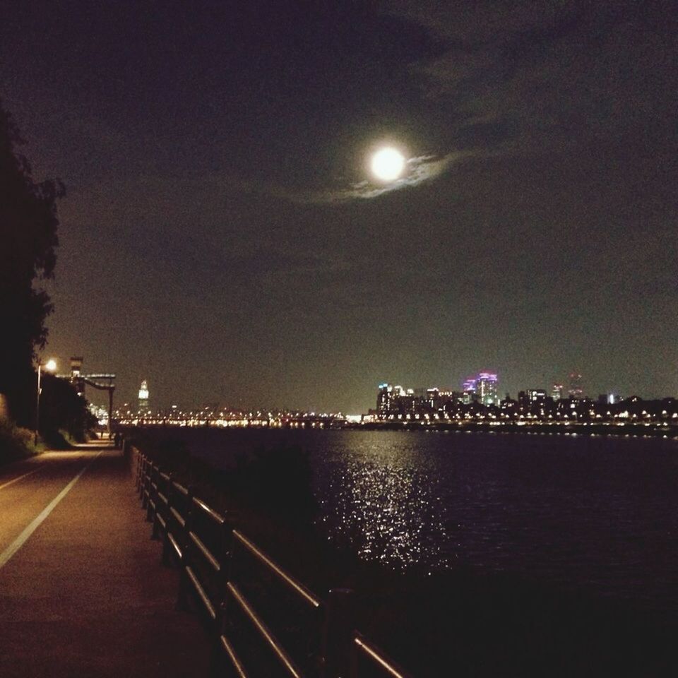 illuminated, night, architecture, built structure, building exterior, city, water, sky, street light, river, lighting equipment, reflection, waterfront, cityscape, bridge - man made structure, light - natural phenomenon, connection, moon, outdoors, the way forward