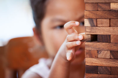 Girl playing with wooden toy blocks while sitting in porch