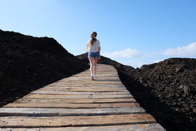 Rear view of woman walking on boardwalk