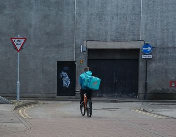 Rear view of man riding bicycle on road