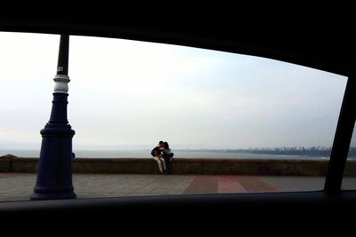 Man cycling on road against sky