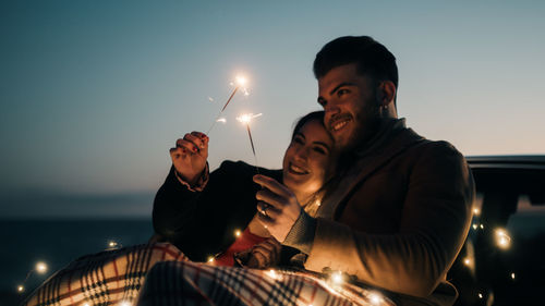 Couple pays with sparkles candles outdoor at the blue hour