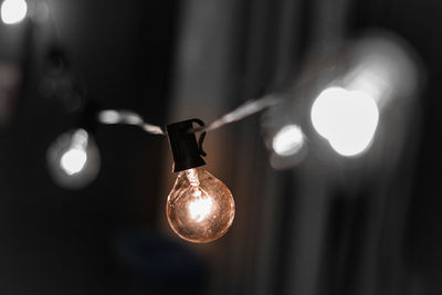 Close-up of illuminated light bulb hanging outdoors