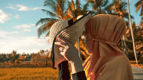 Close-up portrait of woman wearing hat against sky