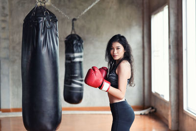 Portrait of young woman practicing with punching bag in studio