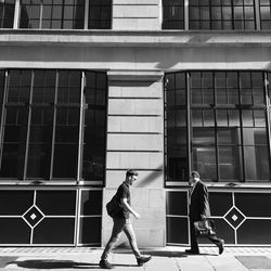 Side view of man walking against building in city