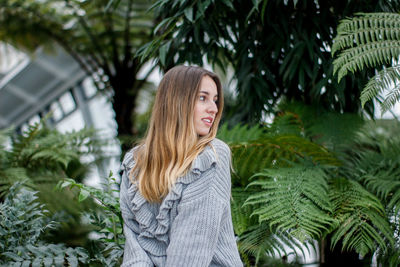 Blond girl looking around in a cold day with vegetation in the background