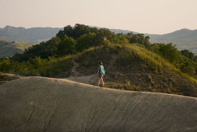 Woman walking on mountain peak against sky