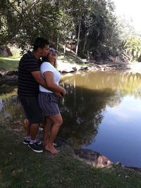 Couple standing by lake against trees