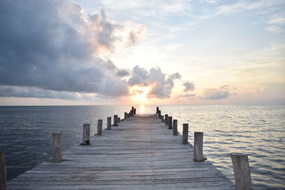 Pier over sea against sky during sunset