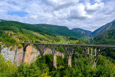 Arch bridge over mountains against sky