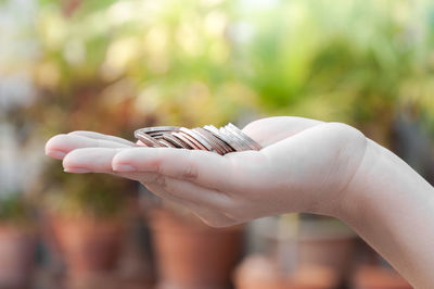 Close-up of person holding coins outdoors
