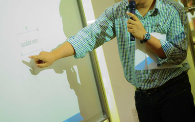 Midsection of businessman talking on microphone while working in board room