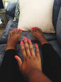 Low section of woman with cropped hand sitting on sofa at home
