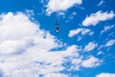 Low angle view of man bungee jumping against sky