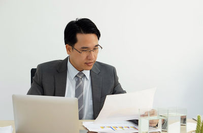 Mid adult man using mobile phone while sitting on table