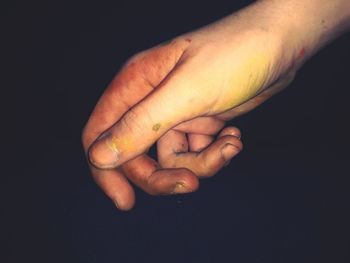 Close-up of man holding hand over black background