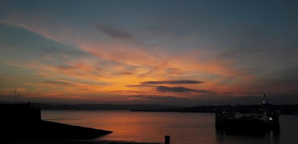 Scenic view of sea against dramatic sky during sunset