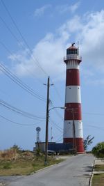 Lighthouse by road against sky